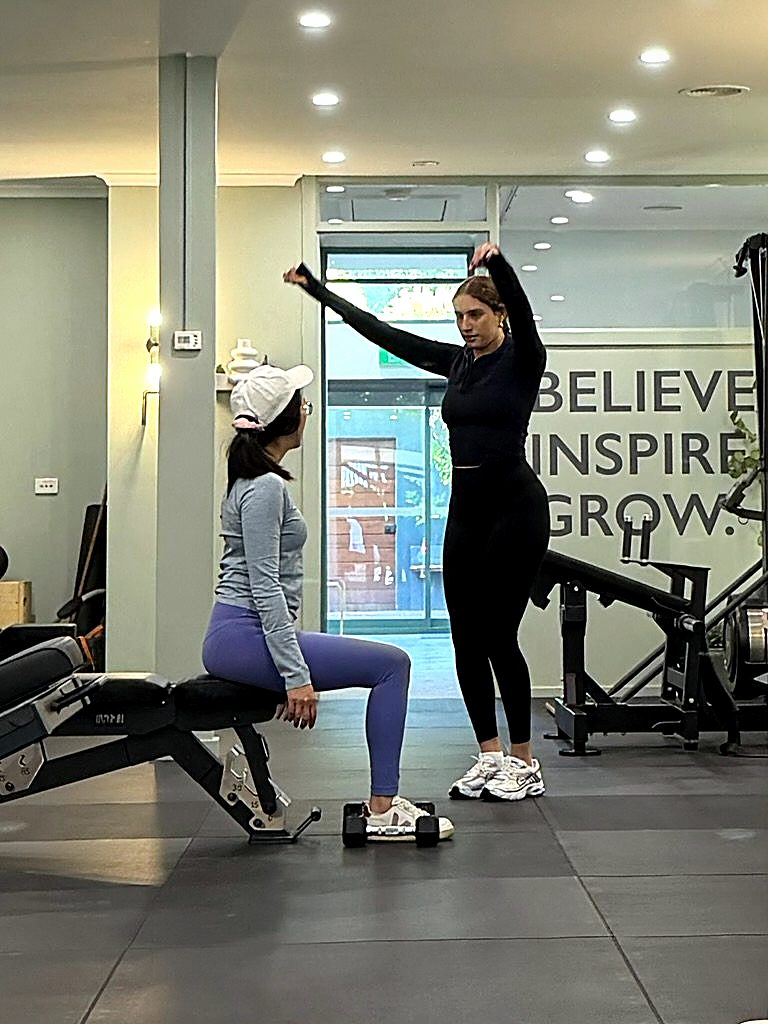 A Synergy coach demonstrating a movement for a client seated on the bench