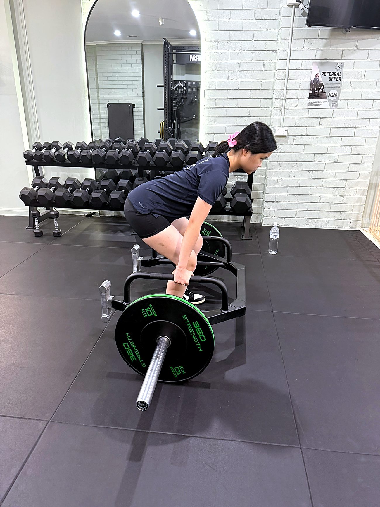 A younger client setting up a trap-bar deadlift on the studio floor