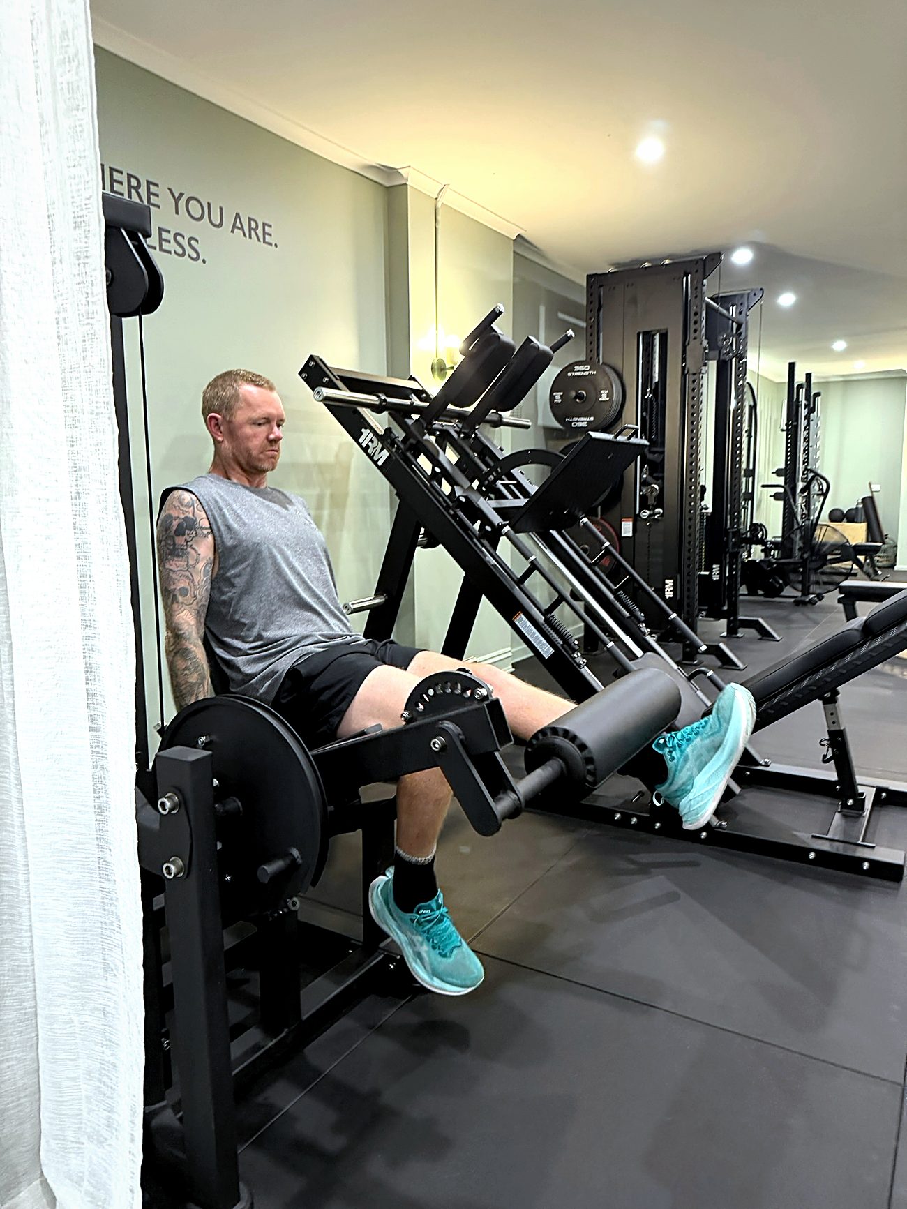 A client on the leg extension beneath the studio wall reading Start where you are, finish limitless