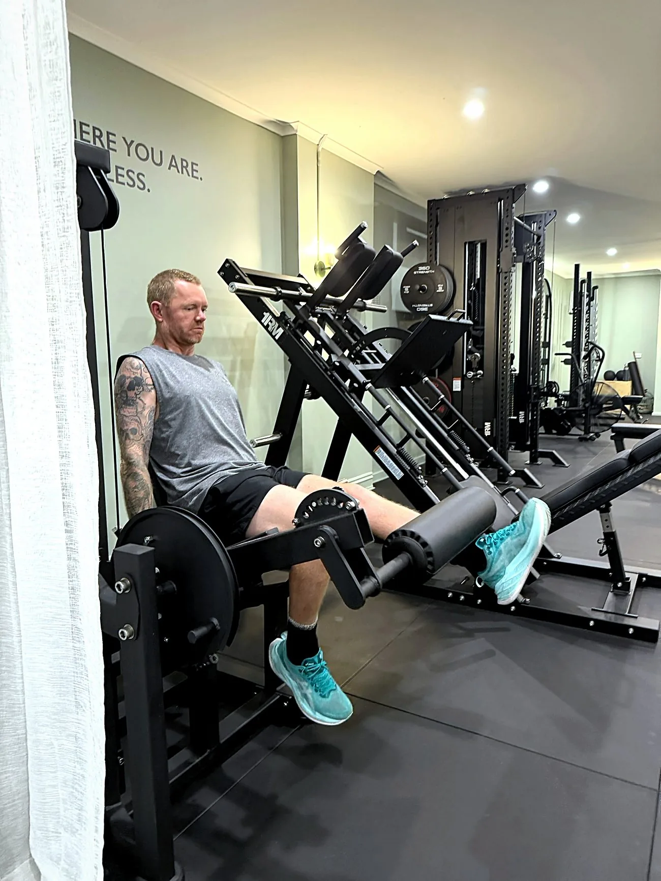 A client on the leg extension beneath the studio wall reading Start where you are, finish limitless