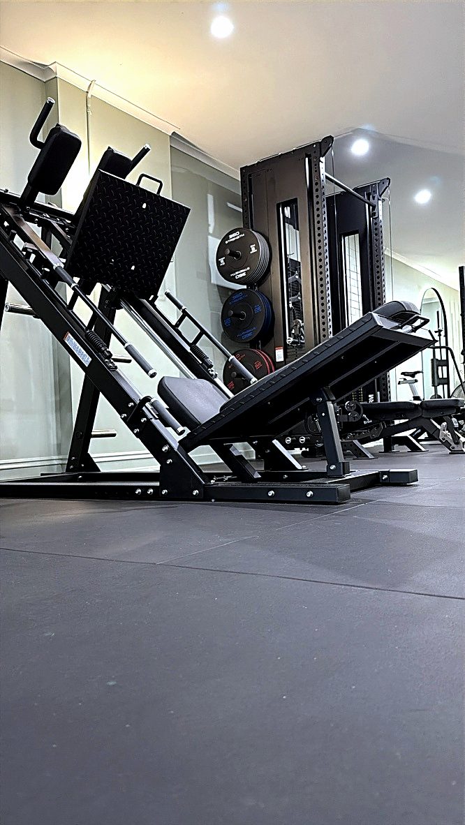 The leg press and loaded plate rack at the far end of the studio floor