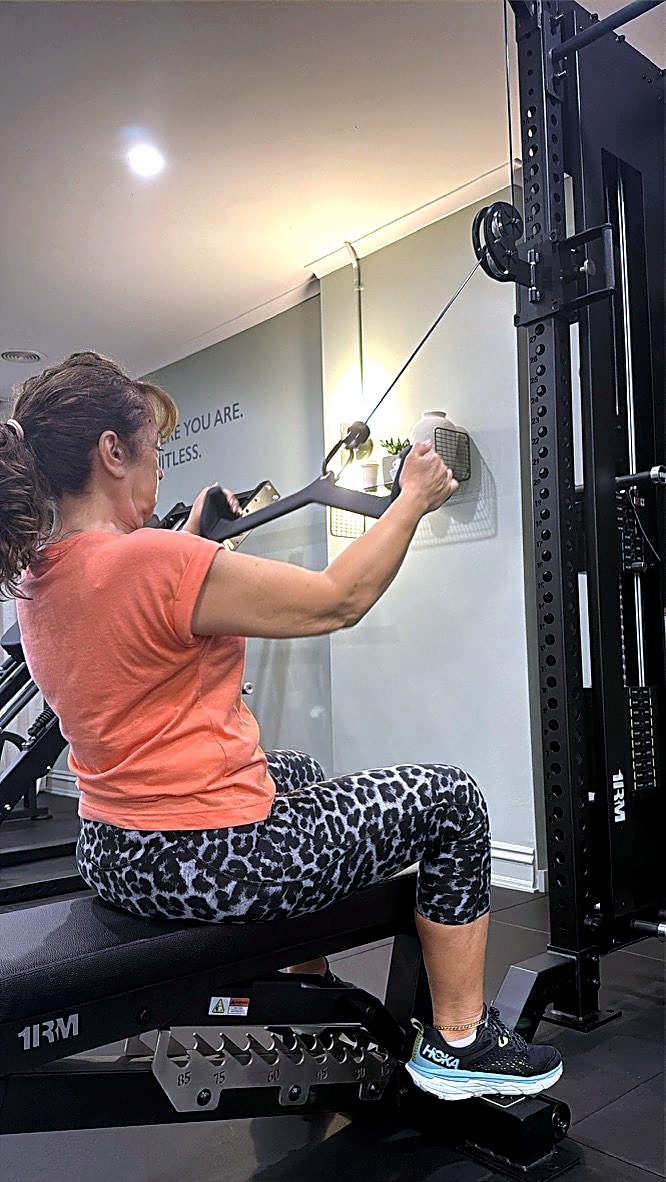 A client in her fifties working a seated cable row at the Synergy studio