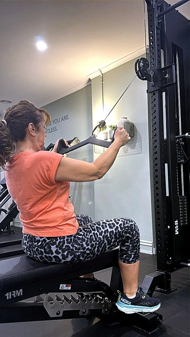 A client in her fifties working a seated cable row at the Synergy studio