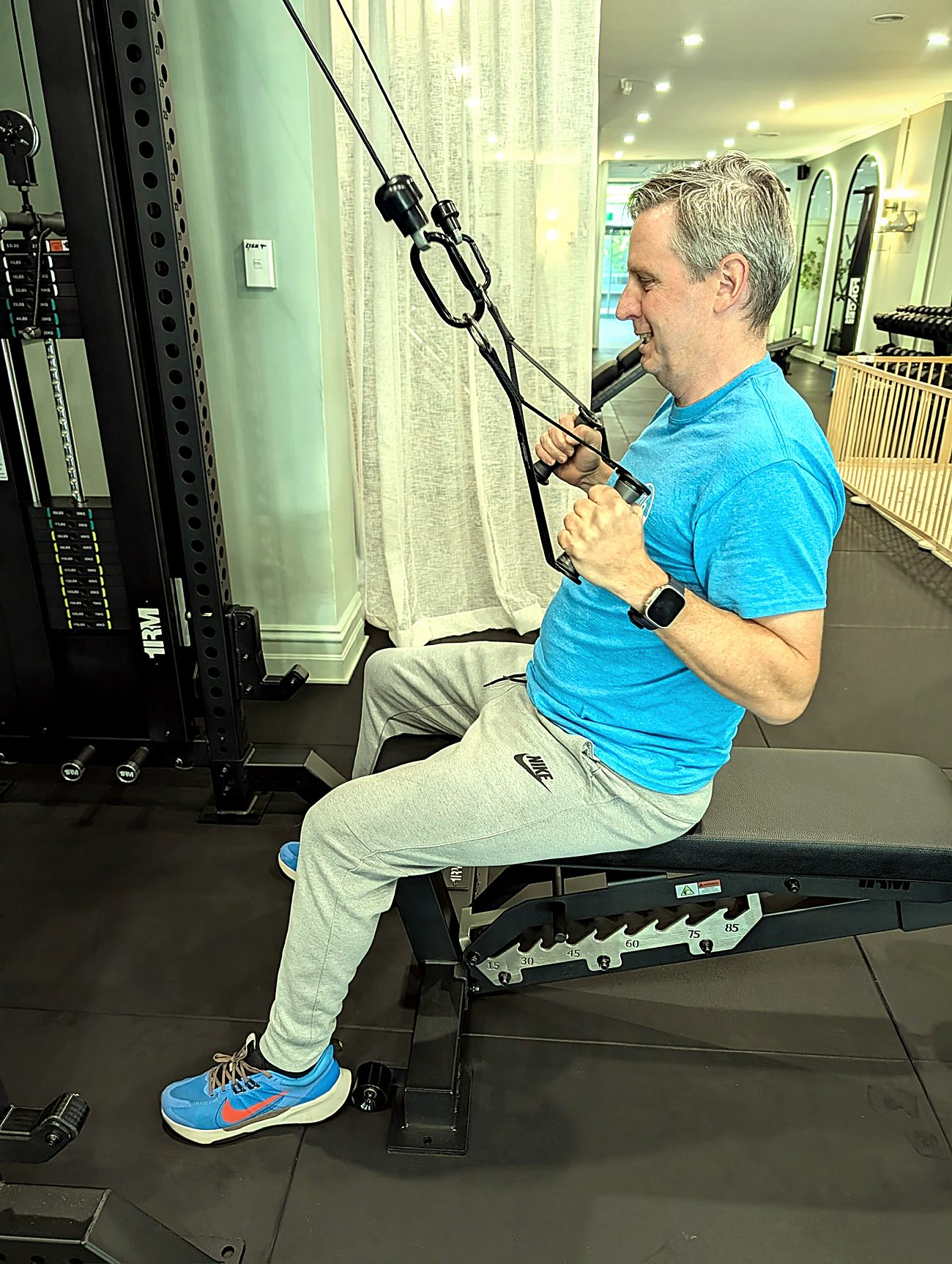 A client in his fifties finishing a seated cable row with his coach's program