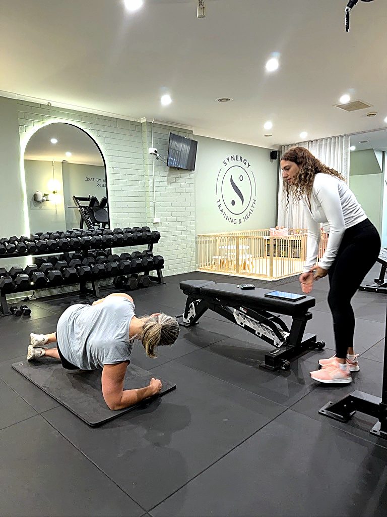 A Synergy coach guiding two clients through their own programs in the same private session